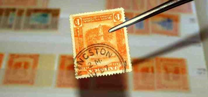 Rare stamp held by tweezers